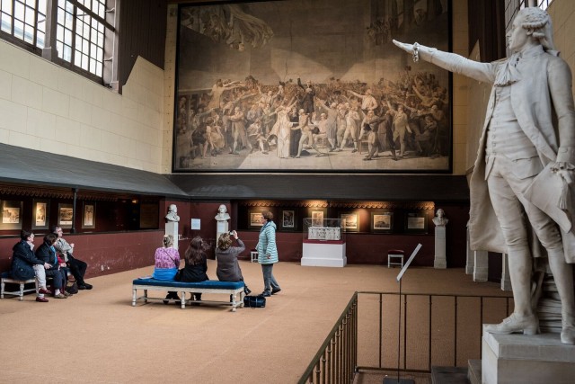 Groupe participant à une visite guidée dans la Salle du Jeu de Paume