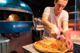 Pizzaiolo découpant une pizza